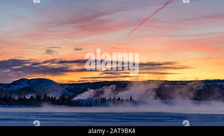 Il vapore sorge dalle caratteristiche geotermiche al tramonto. Parco Nazionale Di Yellowstone, Wyoming, Stati Uniti Foto Stock