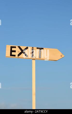 Segno di freccia in legno con la parola uscita. Sullo sfondo il cielo blu. Foto Stock
