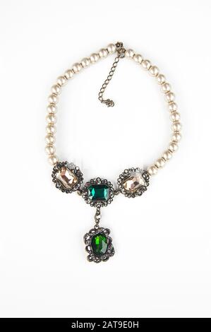 Collana retro gioielli isolato su sfondo chiaro. Questo accessorio di moda ha una stringa di perle e gemme di verde smeraldo. Foto Stock