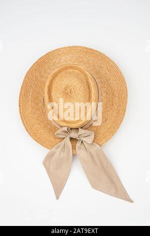 Cappello di paglia isolato su uno sfondo chiaro. Questo cappello da sole è ideale per lavorare in giardino e all'aperto, ha un nastro di tessuto beige legato. Foto Stock