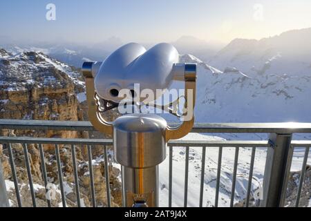 Binocolo a gettoni posto in alto sopra il passo di Pordoi in Italia, si affaccia su un bellissimo panorama di montagna invernale nelle Dolomiti su una brigata Foto Stock