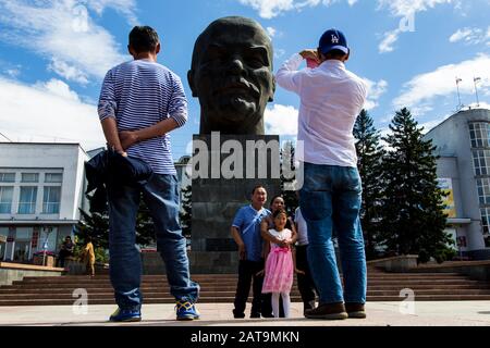 La gente che scatta le immagini davanti alla più grande testa del leader sovietico Vladimir Lenin in in Ulan-Ude Foto Stock