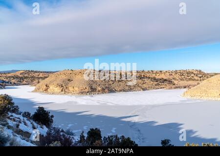 Vasto terreno coperto da un foglio di neve fresca bianca tra colline viste in inverno Foto Stock