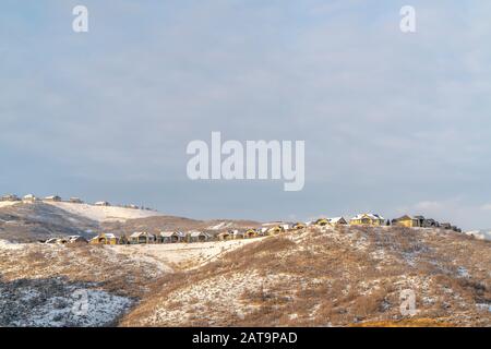 Case nel quartiere accoccolato in cima a colline innevate visto in inverno Foto Stock