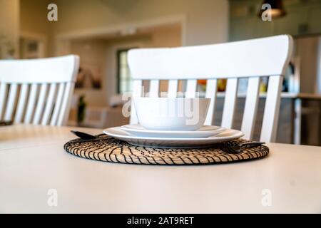 Tavolo da pranzo per famiglie con stoviglie bianche e placemat rotondo Foto Stock