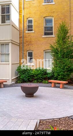 Panchine verticali in pietra intorno ad un camino fuori di un edificio residenziale in una giornata di sole Foto Stock