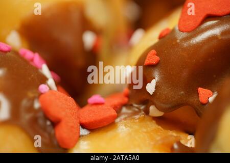 Ciambelle con glassa al cioccolato e spruzzette di cuore di San Valentino Foto Stock