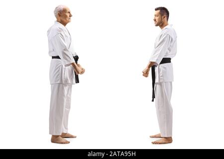 Profilo a tutta lunghezza di un anziano e di un giovane con cintura nera in karate in piedi l'uno di fronte all'altro isolato su sfondo bianco Foto Stock