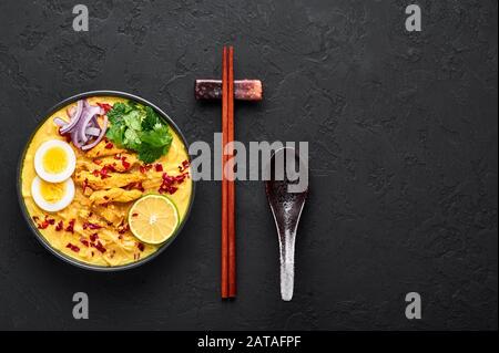 Ohn No Khao Swe in ciotola nera su fondo di ardesia scura. OH No Khao Suey è Coconut Latte Noodle Soup di myanmar cucina con carne di pollo e uova. Bur Foto Stock