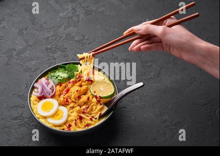 Ohn No Khao Swe in ciotola nera su fondo di ardesia scura. OH No Khao Suey è Coconut Latte Noodle Soup di myanmar cucina con carne di pollo e uova. Bur Foto Stock