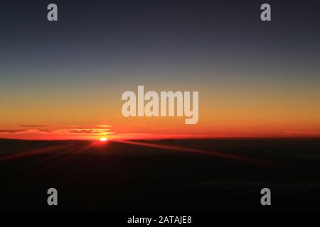 Incredibile vista dell'alba sulle nuvole viste dalla finestra dell'aereo durante il volo Foto Stock