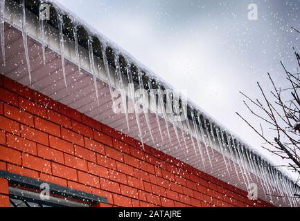 Ghiaccioli sul tetto. Nevicando. Ora invernale. Foto Stock