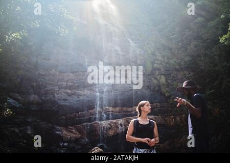 Guida locale che mostra una cascata ad una donna turistica bianca nella gamma Knuckles, Sri Lanka Foto Stock