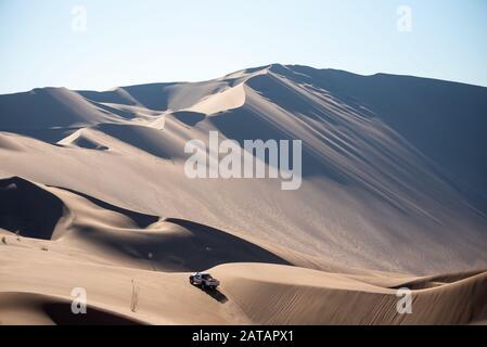 zahedan, baluchestan-iran- luglio 27 2021 vista lontana della pattuglia bianca del nissan pick camion che sale la grande duna di sabbia in dasht e lut o deserto del sahara Foto Stock