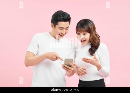 Ritratto di coppia asiatica scioccato o sorpreso di vedere qualcosa sullo smartphone, felice espressione vincente gesto Foto Stock