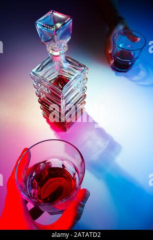 Caraffa quadrata in vetro con liquore e due bicchieri di vetro. Due persone bevono alcolici vista dall'alto Foto Stock