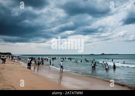 Famiglie dello Sri Lanka che godono di tempo libero su una spiaggia tropicale a Trincomalee. Foto Stock