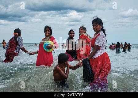 Famiglie dello Sri Lanka che godono di tempo libero su una spiaggia tropicale a Trincomalee. Foto Stock