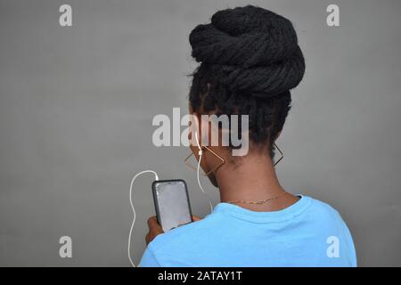 giovane donna nera con acconciatura africana che ascolta musica, vista posteriore Foto Stock