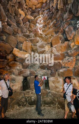 Visitatori in camera interna alla torre centrale di Nuraghe su Nuraxi, 17th secolo a.C., struttura megalitica, età del bronzo, vicino a Barumini, Sardegna, Italia Foto Stock