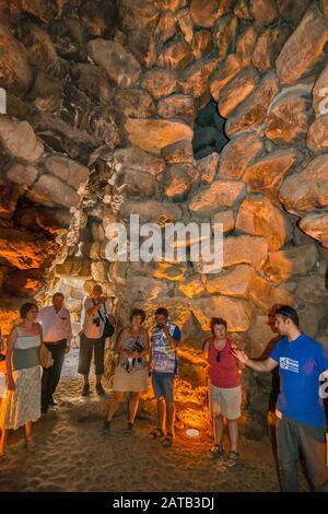 Visitatori in camera interna alla torre centrale di Nuraghe su Nuraxi, 17th secolo a.C., struttura megalitica, età del bronzo, vicino a Barumini, Sardegna, Italia Foto Stock