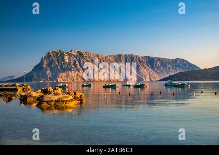 Isola Tavolara, barche, vista all'alba dalla Spiaggia di Cala Suaraccia, spiaggia del Mar Mediterraneo vicino al villaggio di Monte Petrosu, Sardegna, Italia Foto Stock