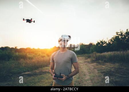 Pilota drone che utilizza drone con telecomando e visore per la realtà virtuale Foto Stock