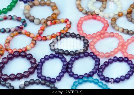 La pietra colorata è usata per fare i bracelets bei. È una credenza religiosa della gente tailandese che avrà buona fortuna per la vendita sul mercato locale dentro Foto Stock