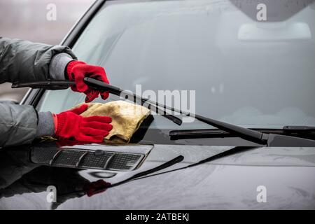 L'uomo tiene la microfibra in mano e lucida il parabrezza. Foto Stock