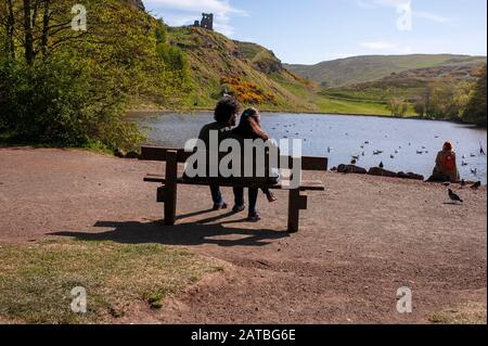 Una coppia gode della vista sul lago di St Margaret e sulle rovine della Cappella di Saint Anthony. Fotografia di viaggio/paesaggio urbano di Edimburgo di Pep Masip. Foto Stock