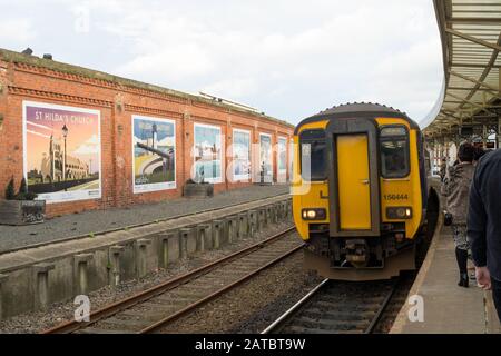 Northern Rail Class 156 Super Sprinter in piedi nella stazione ferroviaria di Hartlepool, con una serie di murales decorativi sullo sfondo, Inghilterra, Regno Unito Foto Stock