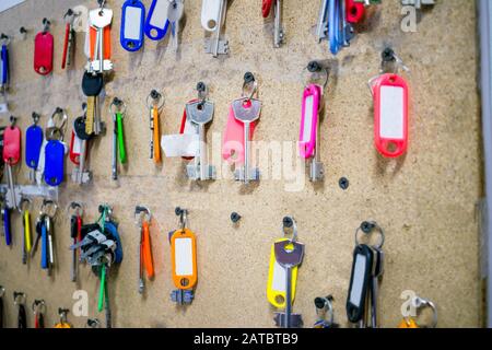 Molti tasti con tag multicolore. Una tavola con un sacco di chiavi della camera pende nell'ostello. Messa a fuoco selettiva Foto Stock