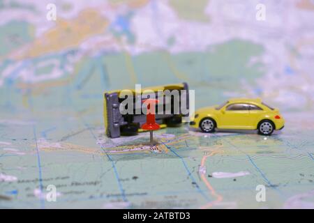 Due macchinine giocattolo si scontrarono sulla mappa geografica del mondo. Incidente di diverse automobili. Incidente su strada. Messa a fuoco selettiva. Foto Stock