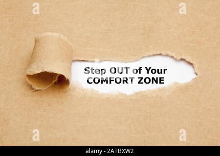 Citazione motivazionale uscire dalla vostra zona di comfort. Apparire dietro carta marrone strappata. Foto Stock