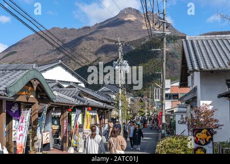 Paesaggio urbano di Yufuin in inverno giorno di sole con cielo blu chiaro. Molti negozi sulla strada, i turisti vengono qui per visite turistiche durante le vacanze di nuovo anno Foto Stock