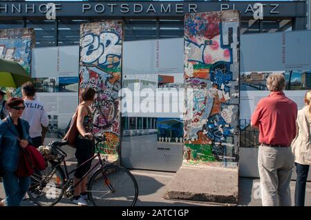 I turisti alla ricerca di sezioni originali del muro di Berlino a Potsdamer Platz a Berlino Germania Foto Stock