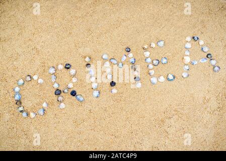 'Crimea' costruita con conchiglie di mare sulla sabbia della costa della Crimea, Russia. Iscrizione con conchiglie sulla spiaggia in Crimea meridionale. Concetto di vacanza estiva Foto Stock