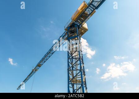 Gru da cantiere sullo sfondo blu del cielo. Vista ad angolo basso del braccio e della torre della gru. Panorama di macchinari pesanti nella soleggiata giornata estiva. Lo Foto Stock