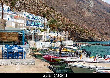 LOUTRO, GRECIA - AGOSTO 2019: Bellissima città con piccolo porto e barche ormeggiate vicino al molo nella parte meridionale dell'isola di Creta Foto Stock