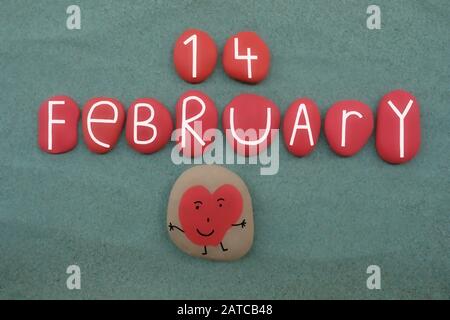 14 febbraio, San Valentino composto con lettere di pietra rossa e un cuore divertente su sabbia verde Foto Stock