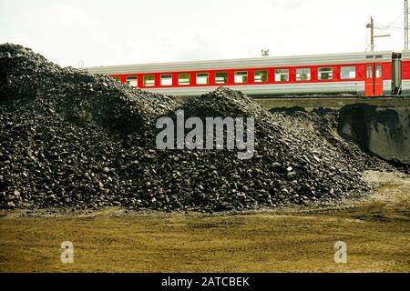 Pile di carbone industriale e di un treno. Combustibili e generazione di energia, tema di inquinamento della natura. Viaggi sostenibili Foto Stock