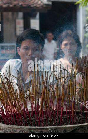 Il popolo asiatico vietnamita illumina le candele e prega su un tempio buddista. Foto Stock