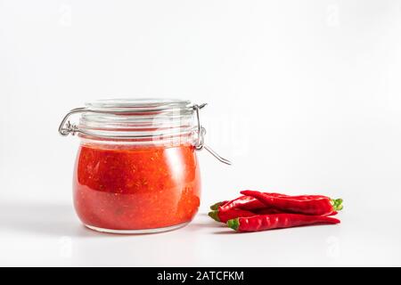 Peperoncino piccante salsa pasta harissa. Adjika. Cucina tradizionale tunisina, georgiana e araba. harissa rosa fatta in casa in un vaso di vetro. Foto Stock