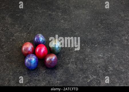 Sei uova di marmo colorate su sfondo scuro Foto Stock