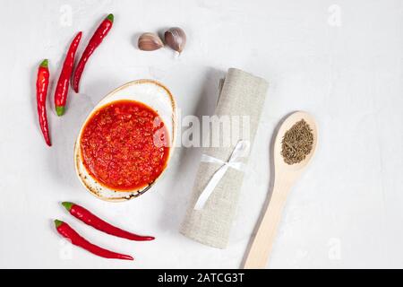 Peperoncino piccante salsa pasta harissa. Adjika su sfondo bianco. Cucina tradizionale tunisina, georgiana e araba. harissa rosa fatta in casa in una ciotola. Foto Stock