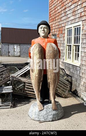 Questa statua in legno intagliato di un pescatore che tiene due banchi di pesce a Peggy's Cove, un piccolo villaggio di pescatori a Nova Scotia a soli 40 km da Halifax. La foto risale a ottobre 2019. Foto Stock