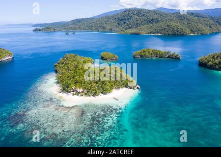 Le molte isole tropicali all'interno di Raja Ampat, Indonesia, sono circondate da incredibili barriere coralline. Questa regione è il centro della biodiversità marina. Foto Stock