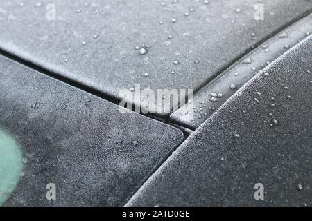 Primo piano della sezione Y del parabrezza posteriore di un'auto, coperto da goccioline di ghiaccio condensate e da un piccolo foglio di ghiaccio Foto Stock