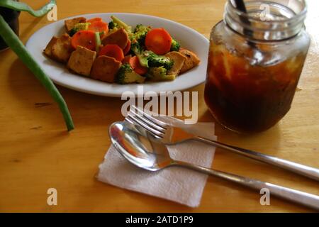 Vista dall'alto di tofu saltato in padella e verdure e caffè freddo, sano pasto vegano a base vegetale Foto Stock