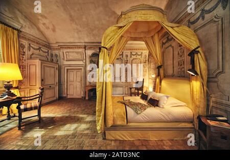 Bella camera da letto dipinta a fresco, letto a baldacchino periodo, drappeggiato con antica damascella reale giallo, lampada, sedia da tavolo Château de Bagnol, Francia Foto Stock